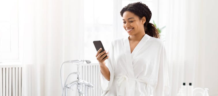A young woman by the phone next to her bathtub.