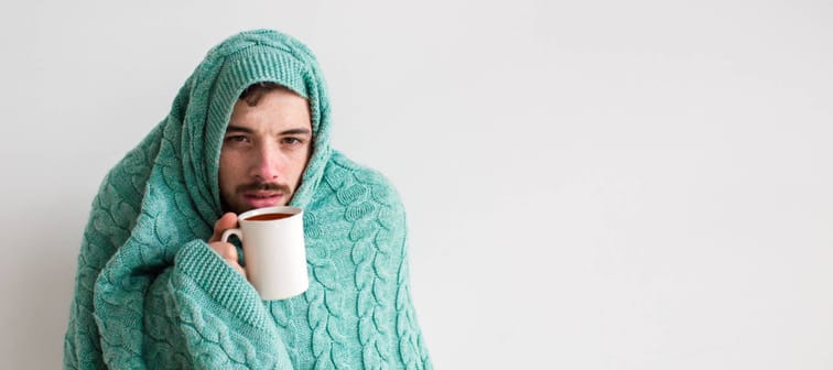 man sick and wrapped in blankets