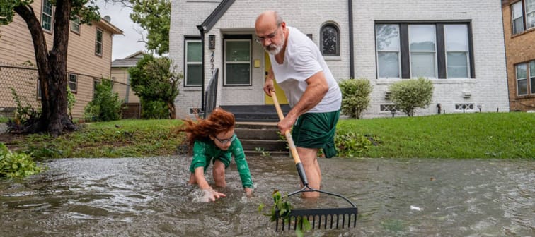 Jack Reyna and his son work to drain floodwater in their neighborhood after Hurricane Beryl swept through the area.