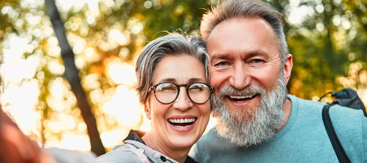 Mature, cheerful couple taking selfie portrait on phone.