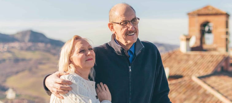 Hugging senior couple in vacation, visiting old Italian town.