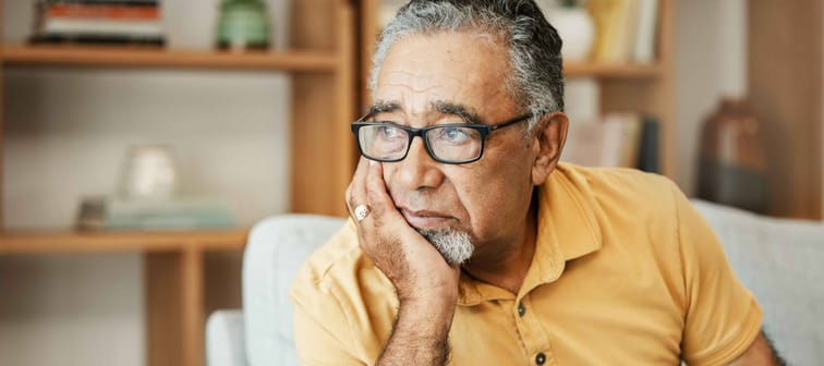 sad old man on a sofa in the living room of his retirement home