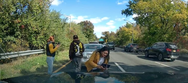 Woman taking photo of vehicle damage in staged car accident