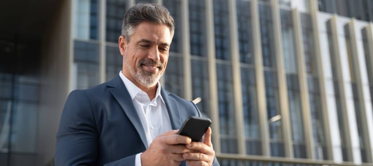 Successful mature hispanic senior business man using smartphone cellphone