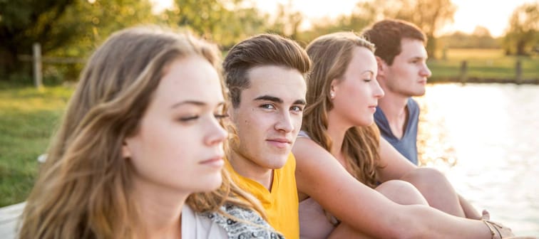 Group of friends sitting by lake, relaxing