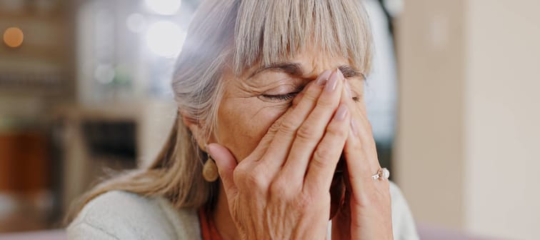 An older woman with her hands in her face.