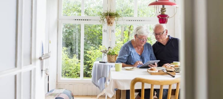Senior woman and man sitting at table and using digital tablet.