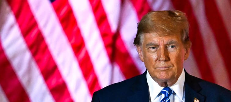 Donald Trump stands in front of an American flag