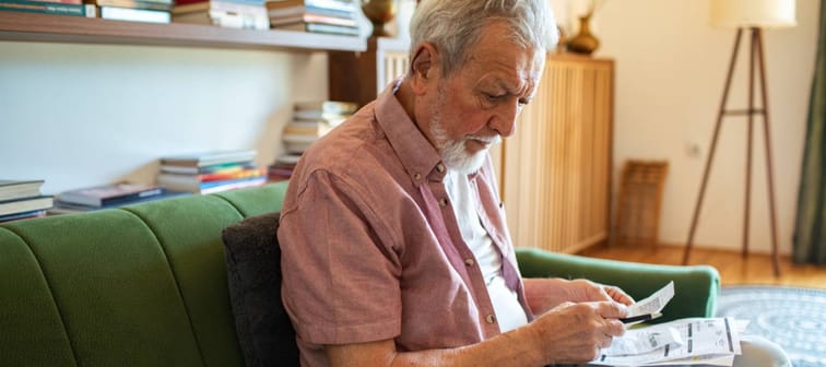 Senior man reviewing utility bills at home with concern