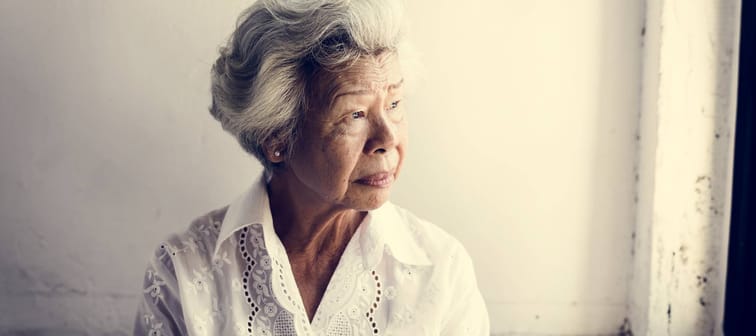 Elderly Asian woman looking out of the window