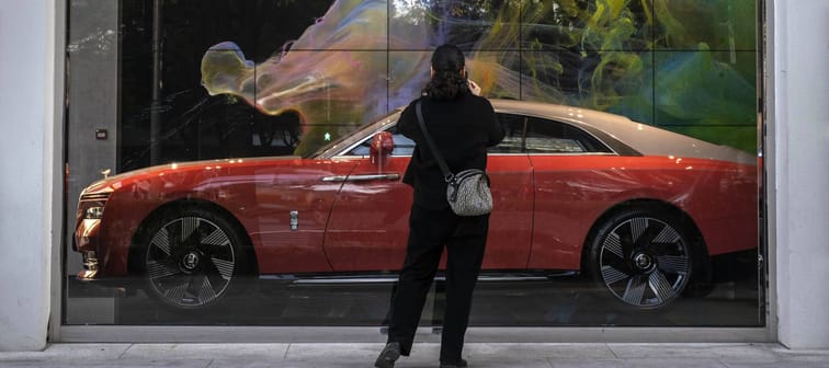 Woman looks at luxury car in showroom.