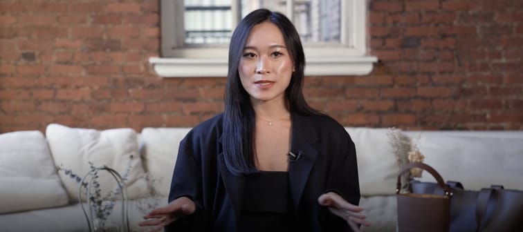 Woman sits in living room, speaking directly to camera. Gesturing to emphasize her words.