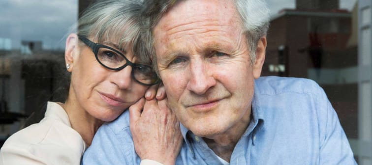 affectionate senior couple sharing a moment by the window overlooking the city