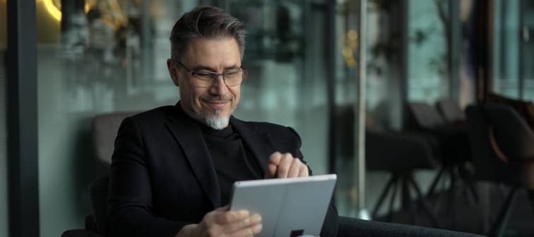 Businessman using tablet computer in office lobby or on cafe terrace