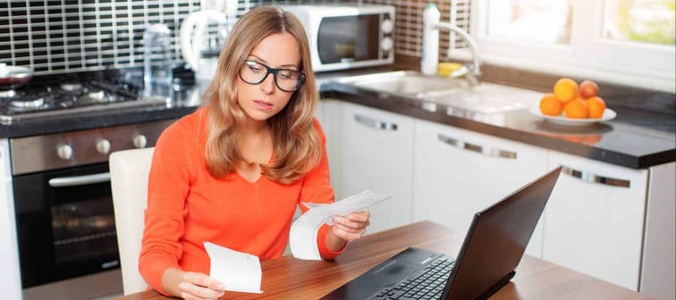 Woman reviewing receipts at her laptop