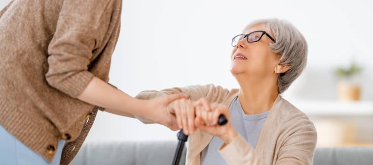 Senior woman getting help getting up with a cane