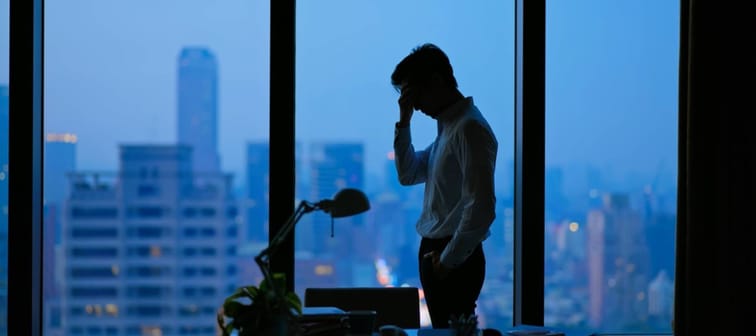 Asian business man being frustrated standing in office hopelessly