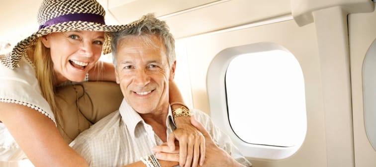 Excited to be headed on holiday. Smiling senior couple on an airplane heading overseas - portrait.