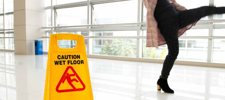 Woman slips next to wet floor sign