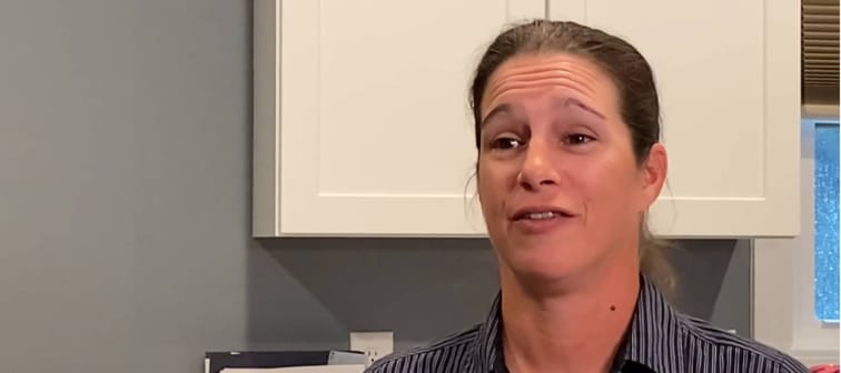 Woman seen talking to camera in kitchen.