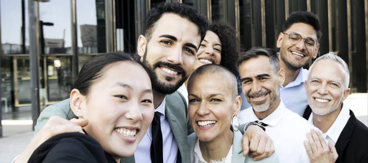 Multiethnic group of cheerful and successful business people taking a selfie outside.