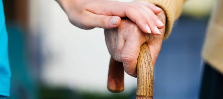 Doctor holding a senior patients 's hand on a walking stick - special medical care concept for Alzheimer 's syndrome.