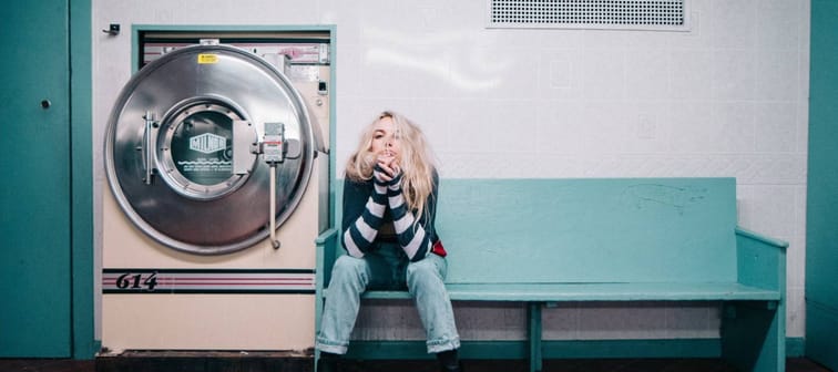 Blonde woman waiting for her clothes at a coin laundry.