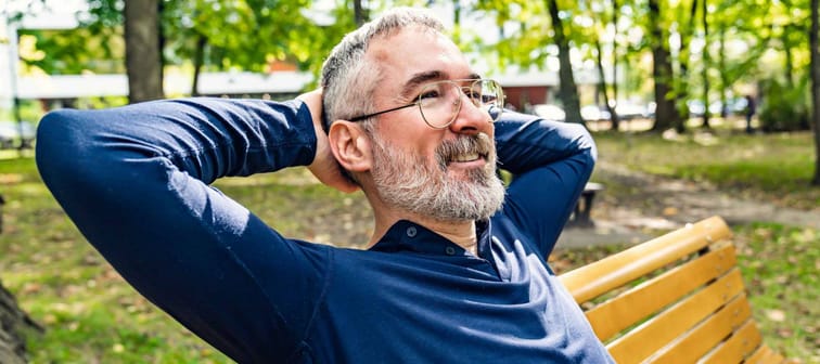 A Portrait of a mature man sitting on a bench in an urban park
