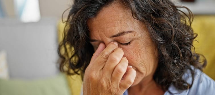 Middle age hispanic woman stressed sitting on sofa at home