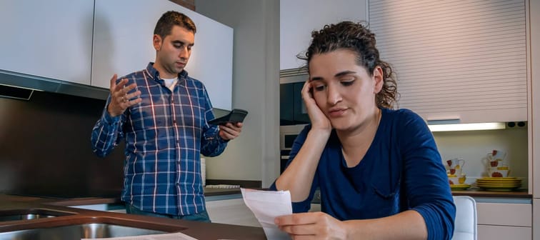 Desperate young couple with debts reviewing their bills in kitchen.