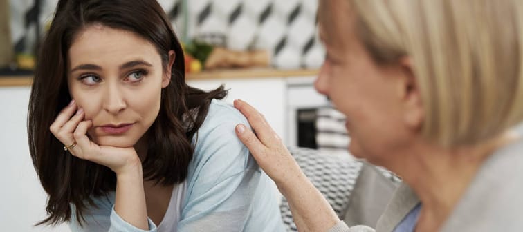 Young woman looking at older woman who is touching her shoulder