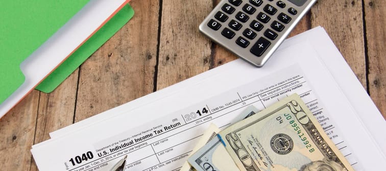 Filing federal taxes for a refund - tax form currency and calculator ona wooden bench