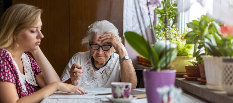 Young woman helping elderly grandmother with paperwork