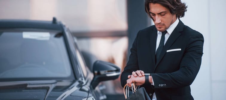 Man looking at watch near his car