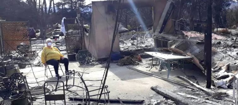 Karen Bagnard sits in chair and surveys ruins of her home.