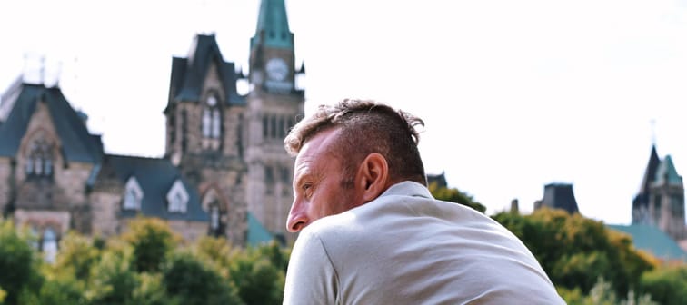 Man leaning on balcony looking at Parliament Hill