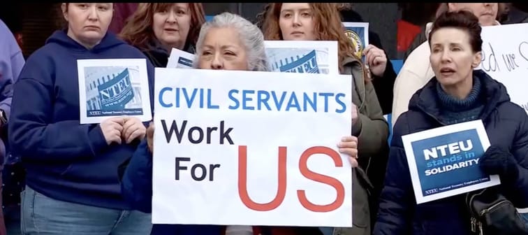 Group of IRS employees hold signs protesting outside Utah building after layoffs announced.