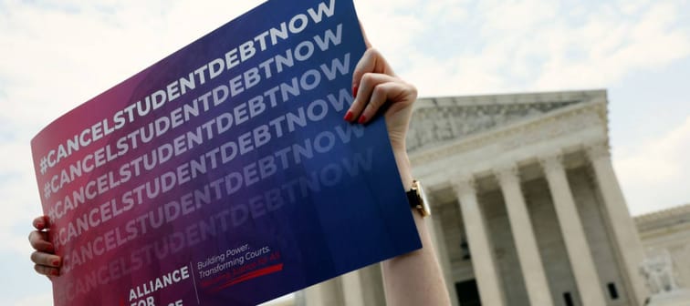 Protester holds 'cancel student loan debt' sign in front of U.S. Supreme Court.