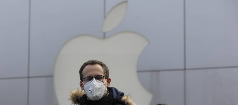 People wear masks as they walk past a closed Apple store at Sanlitun in Beijing, China, 02 February 2020.