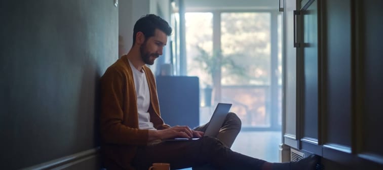 Man sits on floor with computer.