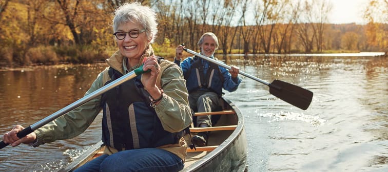 A mature couple going for a canoe ride on a sunny, cool fall day.