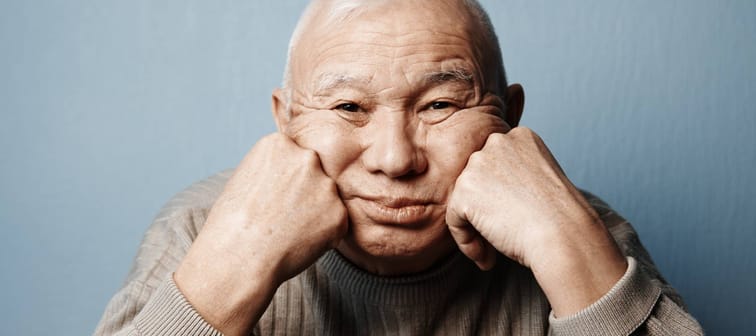 A pensive, older man sitting at a table.