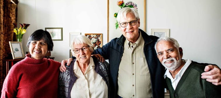 Group of senior friends posing with arms around each other.