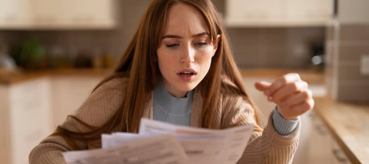 Woman shocked by high bills in the kitchen.