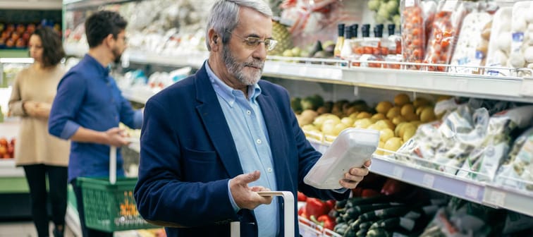 Mature man choosing vegetables in supermarket.