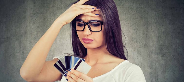 Confused stressed woman looking at too many credit cards full of debt