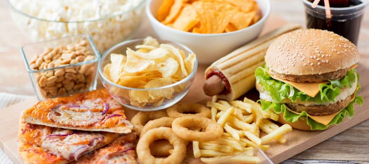 fast food and unhealthy eating concept - close up of fast food snacks and cola drink on wooden table