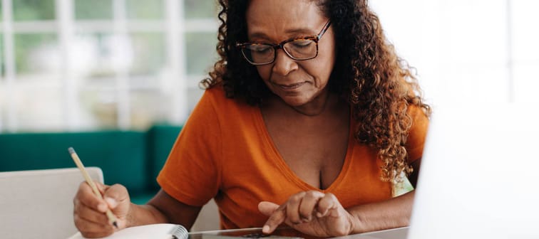Senior woman making calculations on her retirement annuity, reviewing her pension plan and social security benefits.