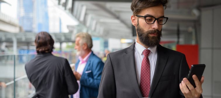 A man dressed in a suit looks at his phone.