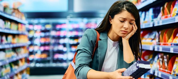 Woman sad looking at grocery item while shopping